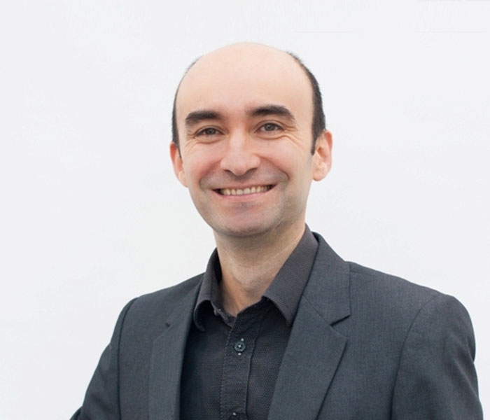 Smiling Dr Gilberto Moreno Bonilla, qualified dermatologist and Mohs micrographic surgery specialist in a dark suit